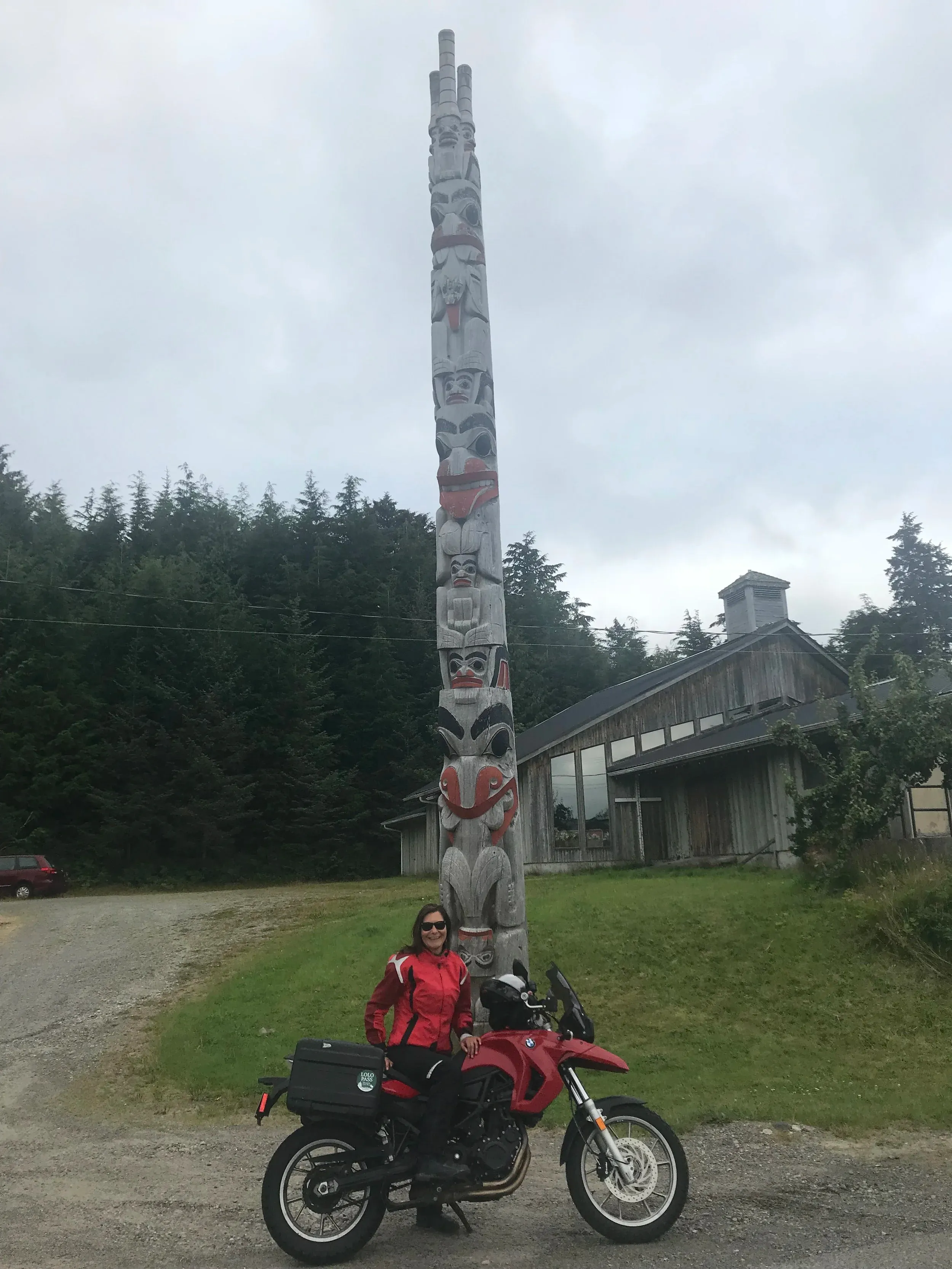 Shelley Nolan, Indigenous founder of Askiwa Motorcycle Tours and trained nurse, astride her BMW motorcycle in front of a traditional totem