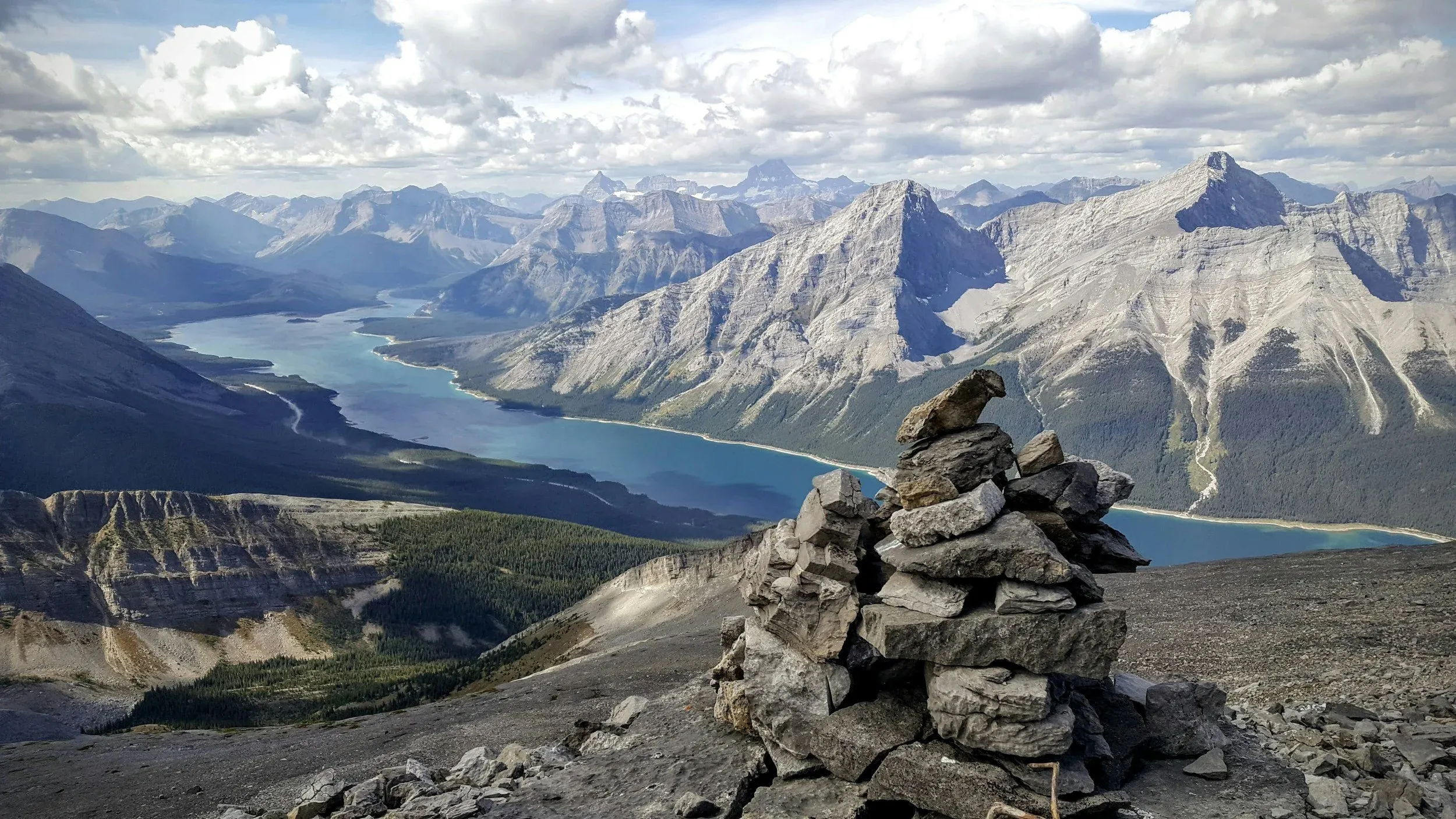 View from the top of a mountain near Canmore, Alberta. Jagged peaks loom across the horizon.